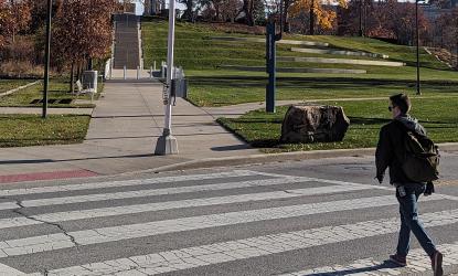 Photo of a pedestrian crossing the street within a marked crosswalk.