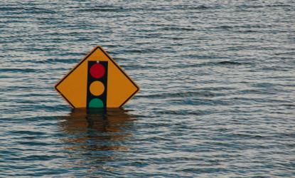photo of flooded water up to a traffic signal sign.