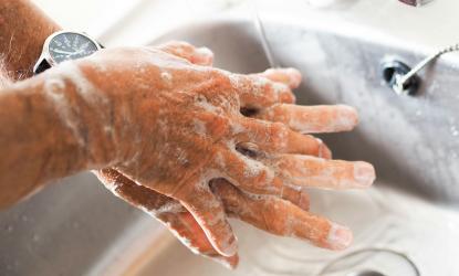 Close up of hands being washed in a sink with soap and water.