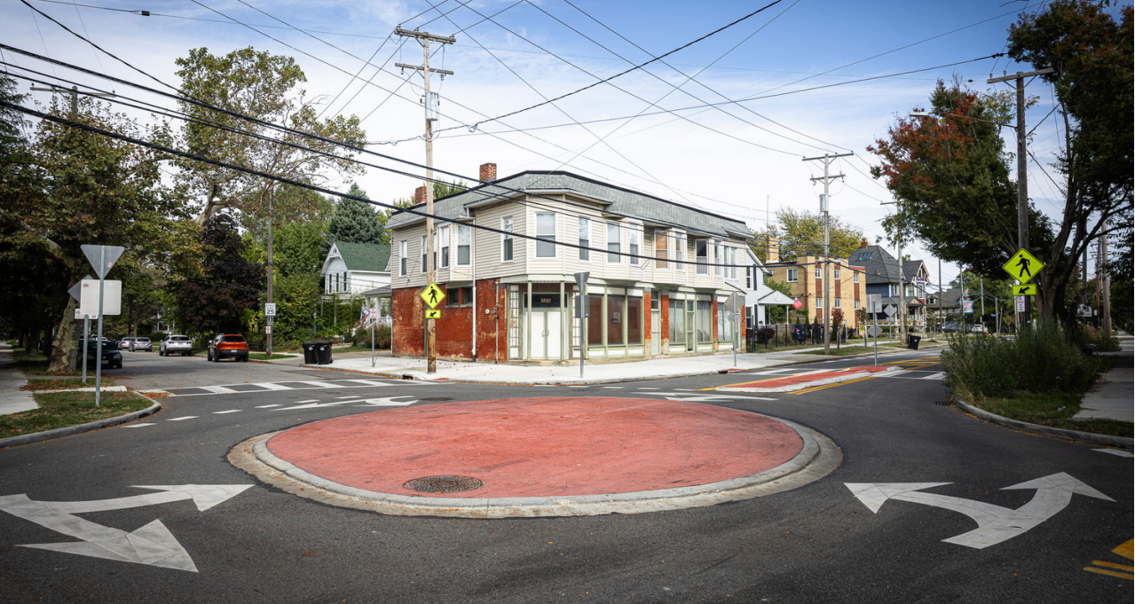 A mini roundabout with a building on the corner in the background
