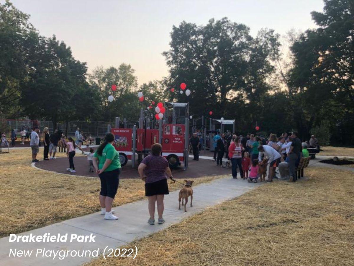 Drakefield Park new playground showing many people crowded around the new red playground with balloons.