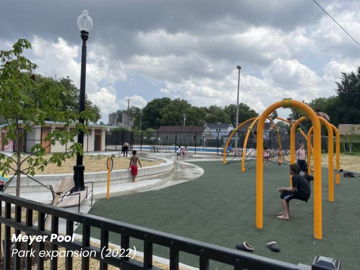 Meyer Pool park expansion showing a new orange playground with kids on the swings and walking around.