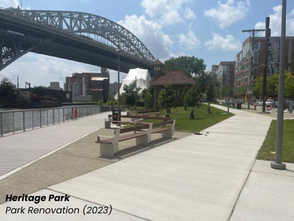 Heritage Park renovation showing a plaza area with walking paths and benches next to a river with a bridge in the background.