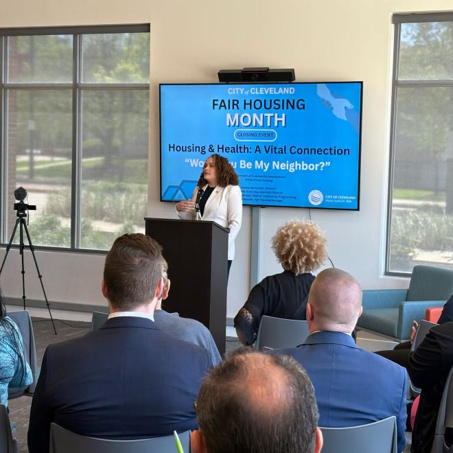 woman at a podium talking to a group about Fair Housing