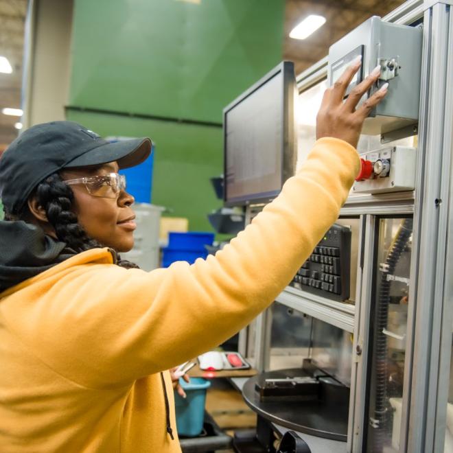 Woman wearing safety glasses adjusting settings on machine