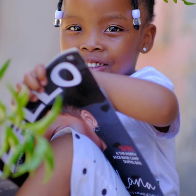 young girl with braids sitting reading wearing polka dot pants