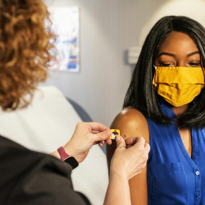 Image of a woman with a mask on getting a vaccine.